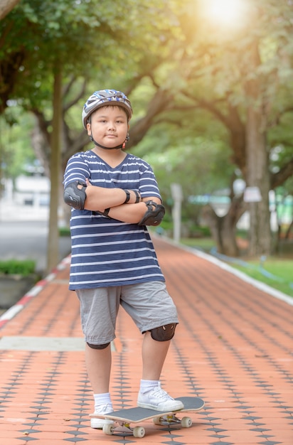 Übergewichtige Junge lernen Skateboard im Fitness-Park fahren