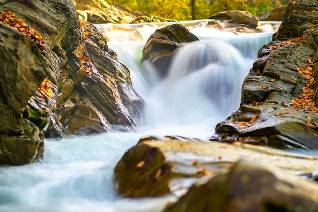 Bergfluss mit kleinem Wasserfall mit klarem türkisfarbenem Wasser, das herunterfällt