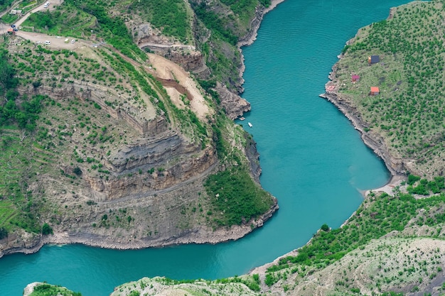 Berglandschaft mit einer tiefen Schlucht mit einem blauen Fluss, entlang dem sich ein Motorboot bewegt