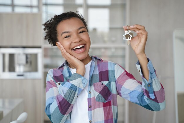 Überglückliche junge Afroamerikanerin hält den Schlüssel vom Kauf einer neuen Wohnung in der Hand