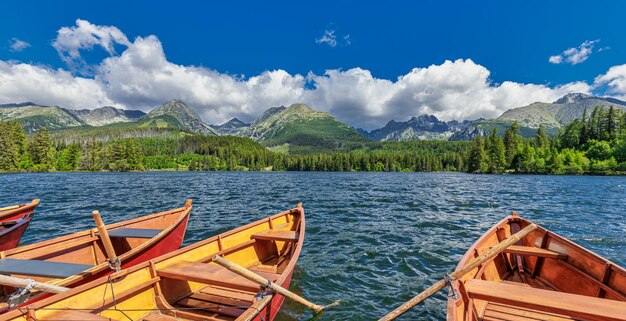 Bergsee mit Nadelwäldern Holzboot sonnig blauer Himmel idyllische Freiheit Reise Hintergrund