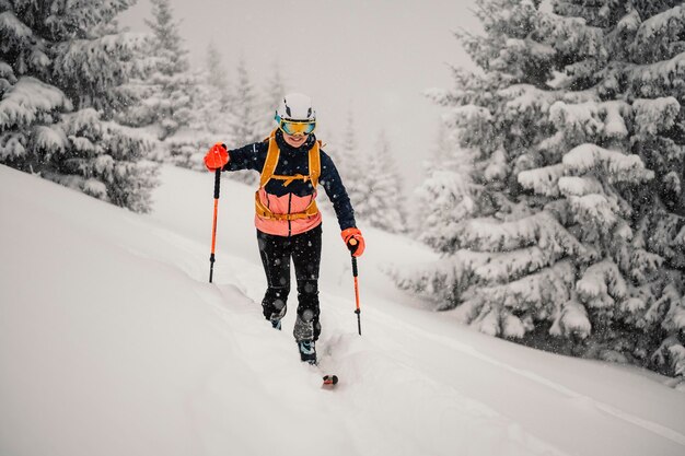 Foto bergsteiger backcountry ski wandern ski frau alpinist in den bergen skitouren in alpiner landschaft mit schneebedeckten bäumen abenteuer wintersport freeride-skifahren