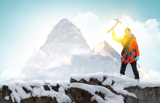 Bergsteiger erreicht die Spitze eines schneebedeckten Berges. Gemischte Medien
