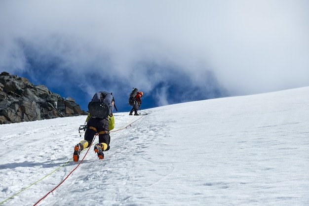 Bergsteiger klettern oder Alpinisten auf den Gipfel eines schneebedeckten Berges