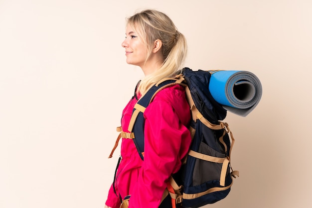 Bergsteigerfrau mit einem großen Rucksack über isoliertem Blick zur Seite