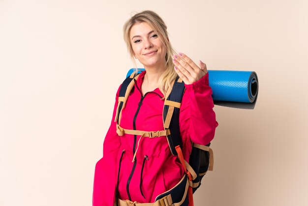 Bergsteigerfrau mit einem großen Rucksack über isoliertem Hintergrund, der einlädt, zu kommen