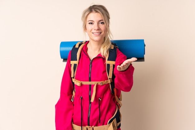 Bergsteigerfrau mit einem großen Rucksack über isoliertem Wandhandschlag nach vielem