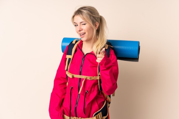 Bergsteigerfrau mit einem großen Rucksack zeigt mit dem Finger auf dich