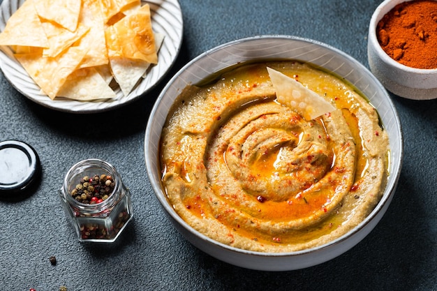 Berinjela árabe tradicional mergulho baba ganoush com ervas e páprica defumada em fundo escuro. Húmus de berinjela. Babaganush ou caviar de berinjela. Berinjela assada. Molho turco de berinjela