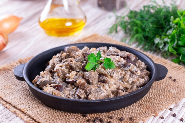 Berinjela cozida com legumes e creme de leite em uma panela sobre uma mesa de madeira