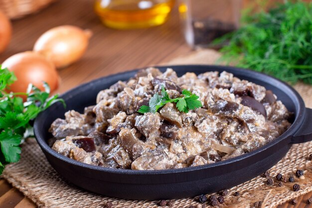 Berinjela cozida com legumes e creme de leite em uma panela sobre uma mesa de madeira