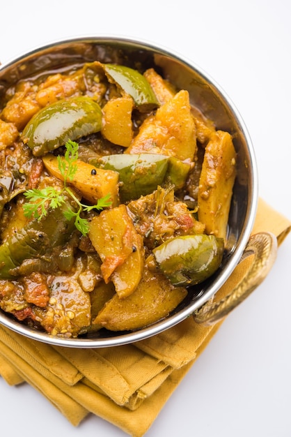 Berinjela picante indiana caseira e curry de batata, também conhecido como aloo Baigan ki sabzi em hindi, servido em kadhai ou tigela branca, foco seletivo
