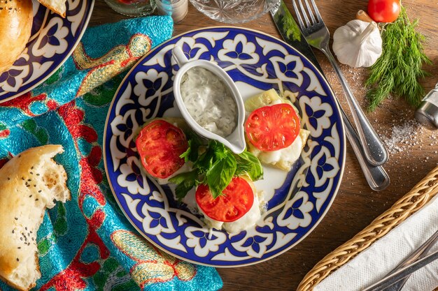 Berinjela síria assada com queijo Suluguni e gouda com molho de alho em um prato com padrão tradicional uzbeque.