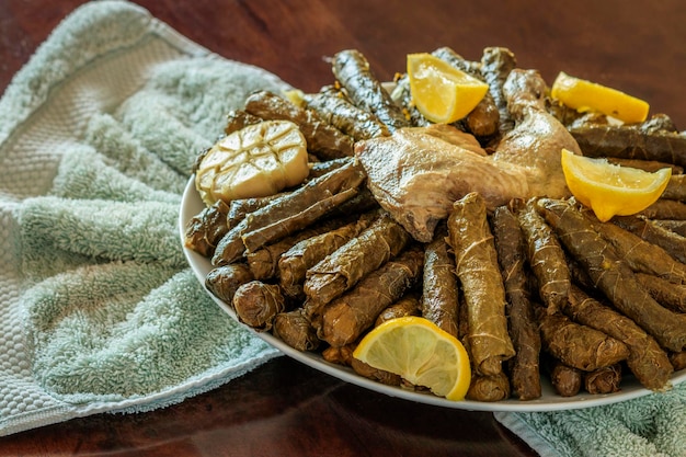 Überkopfaufnahme einer traditionellen arabischen Mahlzeit aus Weinblättern mit Hühnerfleisch, serviert mit Zitronen