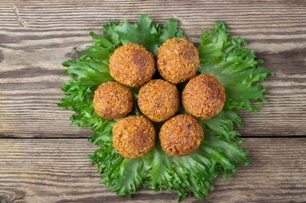 Überkopfbild der arabischen Snackfalafel in Form von Kichererbsenbällchen mit Gewürzen. Holzhintergrund.