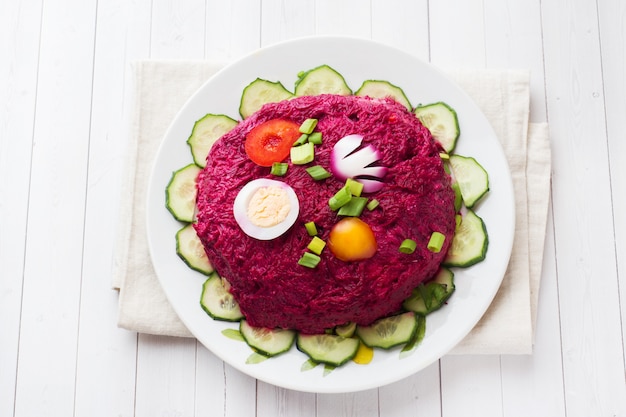 Überlagerter Salat mit Hering und roten Rüben, Karotten und Kartoffeln und Eiernahaufnahme auf einer Platte.