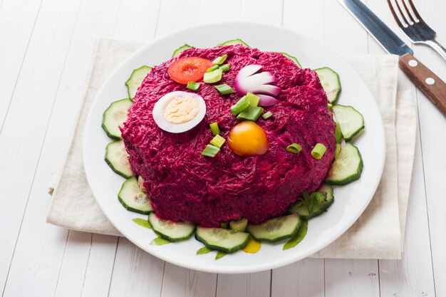 Überlagerter Salat mit Hering und roten Rüben, Karotten und Kartoffeln und Eiernahaufnahme auf einer Platte.