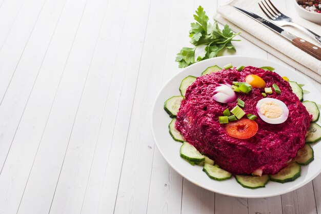 Überlagerter Salat mit Hering und roten Rüben, Karotten und Kartoffeln und Eiernahaufnahme auf einer Platte.