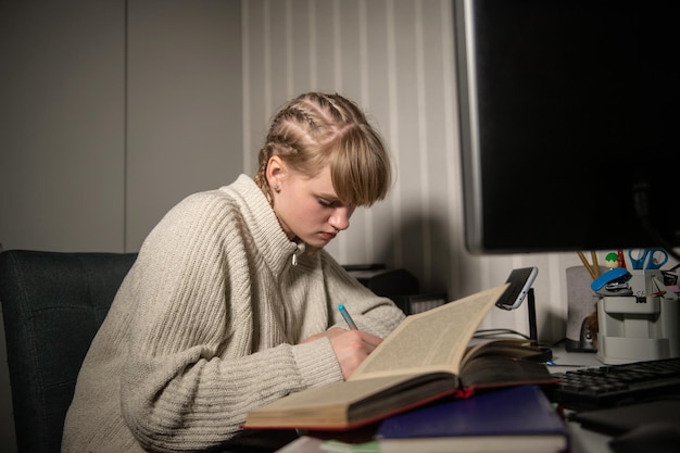 Überlastung und Schlaflosigkeit durch Verarbeitung in der Nacht. Nachts im Dunkeln in der Nähe des Computers ein Buch lesen