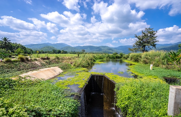 Überlauf des Wehrs und des Berges mit schönem blauem Himmel