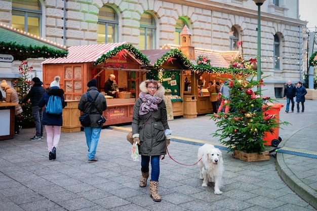 Berlim, Alemanha - 12 de dezembro de 2017: Mulher com cachorro labrador retriever em barracas decoradas de Natal no mercado de Natal perto da Ópera em Berlim na Alemanha na Europa no inverno