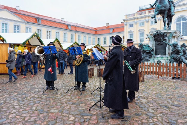 Berlim, alemanha - 9 de dezembro de 2017: grupo musical tocando no mercado de natal perto do palácio de charlottenburg em berlim de inverno, alemanha. decoração da feira do advento e as barracas com itens de artesanato