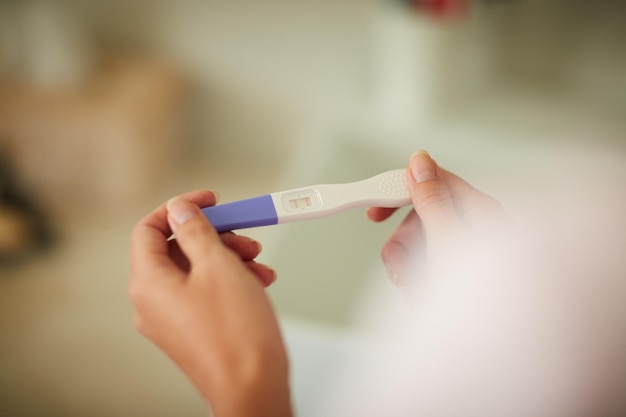 Überprüfung der Ergebnisse ihres Schwangerschaftstests Schnappschuss einer nicht erkennbaren Frau, die zu Hause im Badezimmer einen Schwangerschaftstest hält
