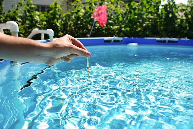 Überprüfung der Wasserqualität eines Pools mit Hilfe eines Teststreifens mit pH-Wert Chlor und Algizid