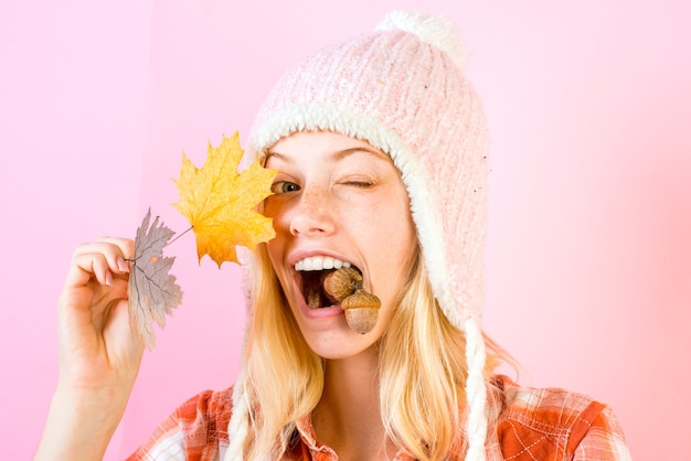 Überraschen Sie Frau, die mit Herbstlaub spielt und Kamera betrachtet.