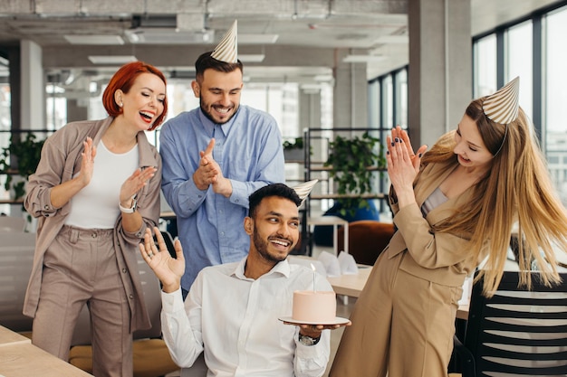 Überraschen Sie glückliche Leute der gemischten Rasse, die einen Geburtstag des Kollegen im modernen officexA feiern