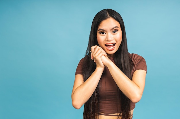 Überrascht erstaunt schockiert asiatische Frau Blick in die Kamera erfreut mit glücklichem und lächelndem Gesicht Ausdrucksstarker Ausdruck Hübsches Mädchen wirkt wie ein glückliches Produkt, das auf blauem Hintergrund isoliert ist