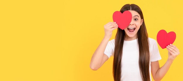 Überrascht jugendlich Mädchen mit Valentinsherz auf gelbem Hintergrund Liebestag Kind Mädchen Porträt