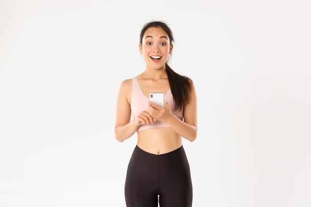 Überrascht und erstaunt asiatische Sportlerin, Sportlerin sagen wow, überprüfen Fitness-App auf Handy.n.