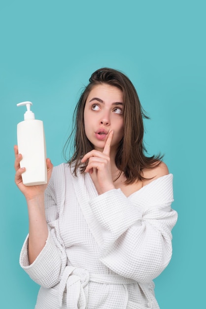 Überrascht verblüffte Frau hält Flasche Shampoo und Conditioner