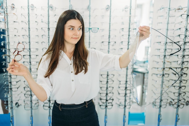 Überraschte Dame hält riesige Brille im Optikladen