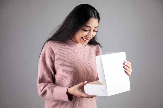 Überraschte Frau, die Geschenkbox hält