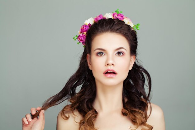 Überraschte Frau mit perfekter Frisur und Make-up auf grauem Hintergrund