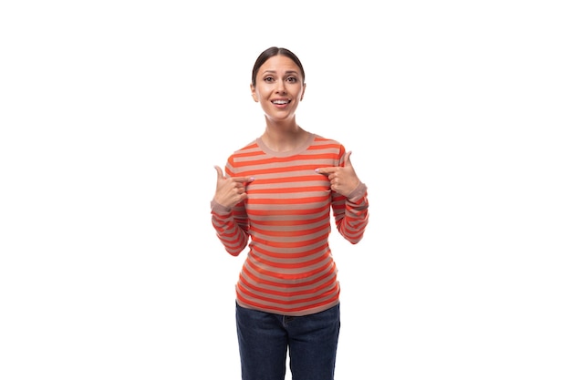 Überraschte junge erwachsene Frau, gekleidet in einen orangefarbenen Pullover, zeigt sich mit den Händen