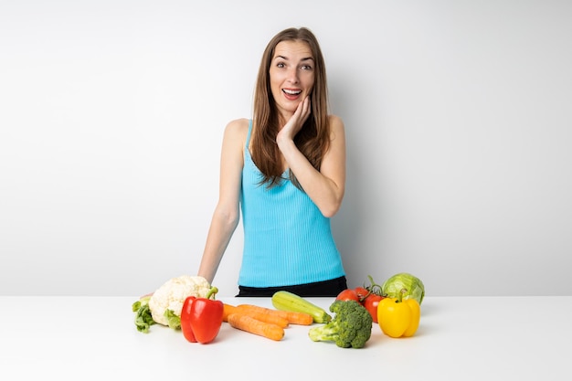 Überraschte junge Frau in der Küche liegt frisches Gemüse auf dem Tisch