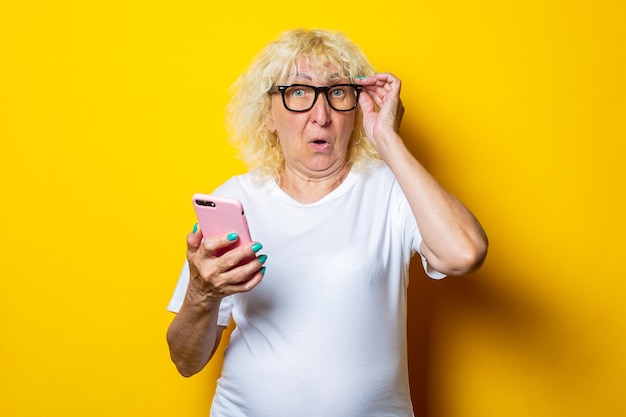 Überraschte schockierte alte Frau, die Telefon hält