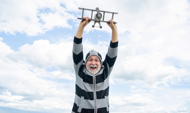 Überraschter älterer Mann im Ruhestand reifer Mann im Ruhestand alter Mann auf Himmelshintergrund mit Spielzeugflugzeug
