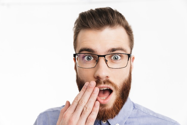 Überraschter bärtiger eleganter Mann mit Brille, die seinen Mund bedeckt und schaut