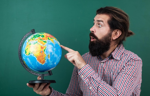 Überraschter bärtiger Mann im karierten Hemd, der auf die Schulausbildung der Geographie der Erdkugel blickt