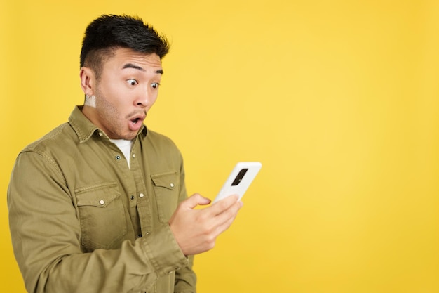 Überraschter chinesischer Mann, der den Bildschirm eines Handys betrachtet
