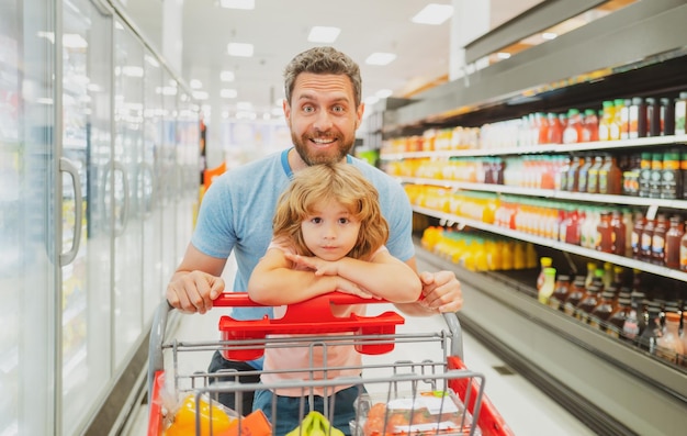 Überraschter Familienvater und Sohn mit Einkaufswagen beim Kauf von Lebensmitteln im Lebensmittelgeschäft oder Supermarkt Überraschtes Gesicht Man Shopper mit Lebensmitteln