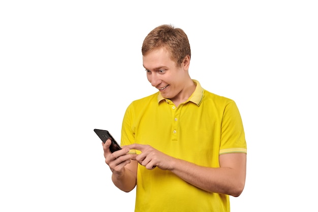 Überraschter junger Mann mit dem lustigen Kerl des Smartphones, der das Telefon lokalisiert auf weißem Hintergrund hält