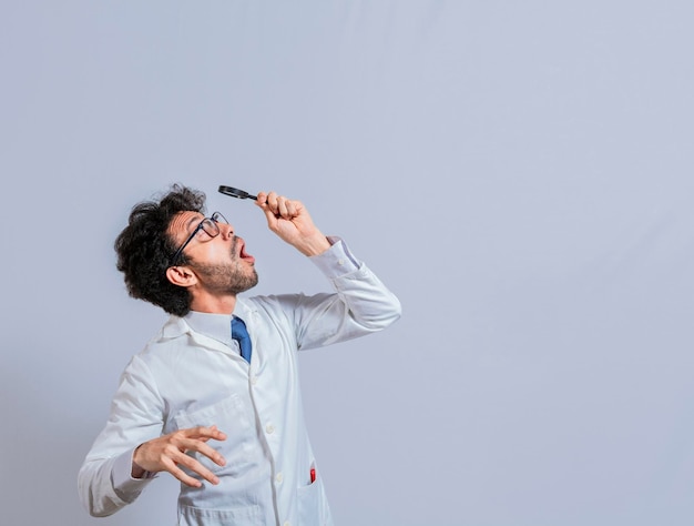 Überraschter Mann im Laborkittel mit Lupe, der eine Anzeige oben betrachtet Wissenschaftlermann, der mit einer Lupe nach oben schaut Erstaunter Mann, der eine Anzeige mit einer Lupe beobachtet