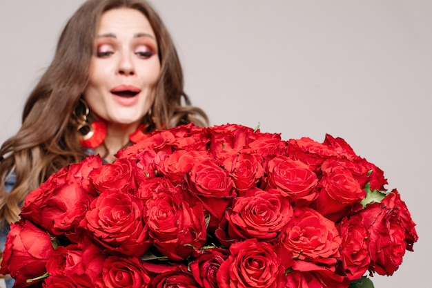 Überraschter und glücklicher Brunette überrascht mit Rosen