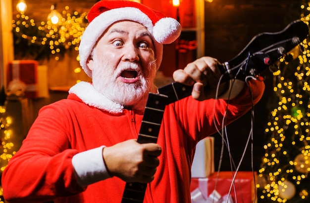 Überraschter weihnachtsmann mit defekter e-gitarre frohe weihnachten und guten rutsch ins neue jahr weihnachtszeit