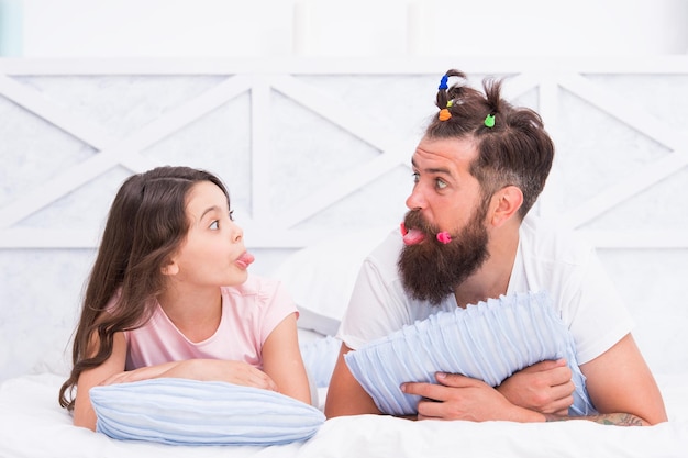 Überraschtes Kind, das Vater mit lustigem Haarschnitt anschaut, entspannt sich am Wochenende in der Freizeit